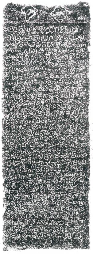 An ink impression of one face of a pillar. A conch and a discus are carved at the top, above rows of pale letters.