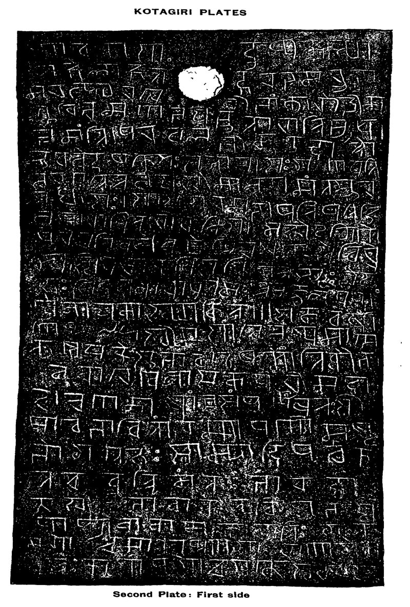 A dark photograph of the second Kotagiri copper plate. Pale Devanagari-like letters fill the plate, and a round white hole is cut near the top.