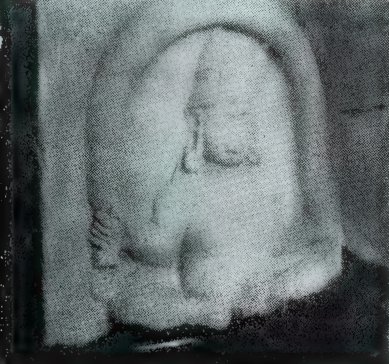 A worn, rounded stone carving of a squat being inside an arched frame, against a dark background.