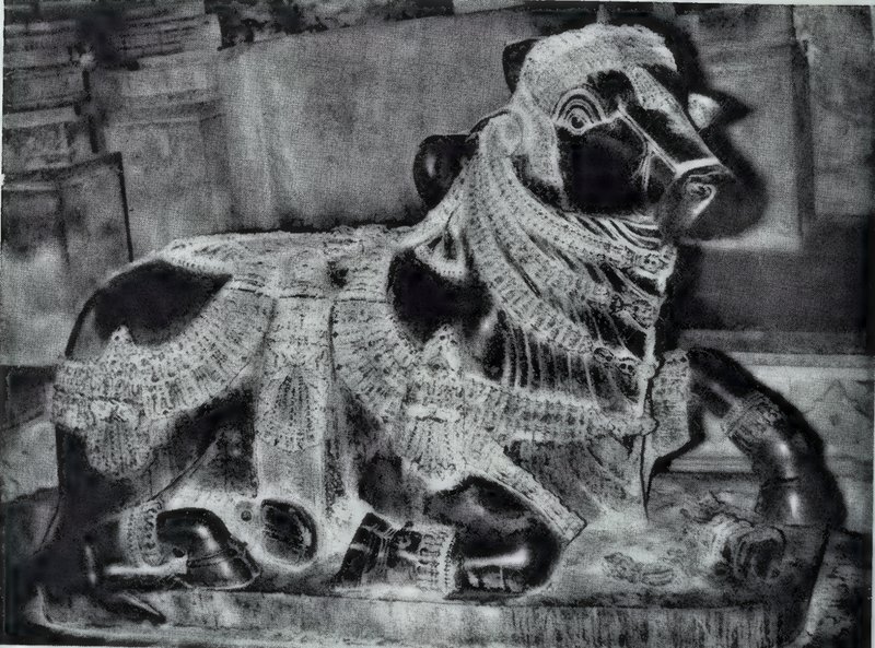 A large seated stone bull wearing richly carved chains, bells and garlands.