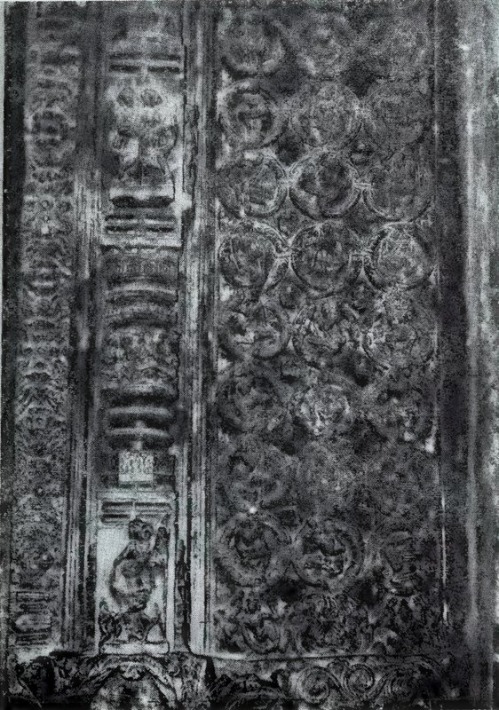 A dark, densely carved stone surface with tiny dancers inside circular scrolls and a column of small panels at the left.