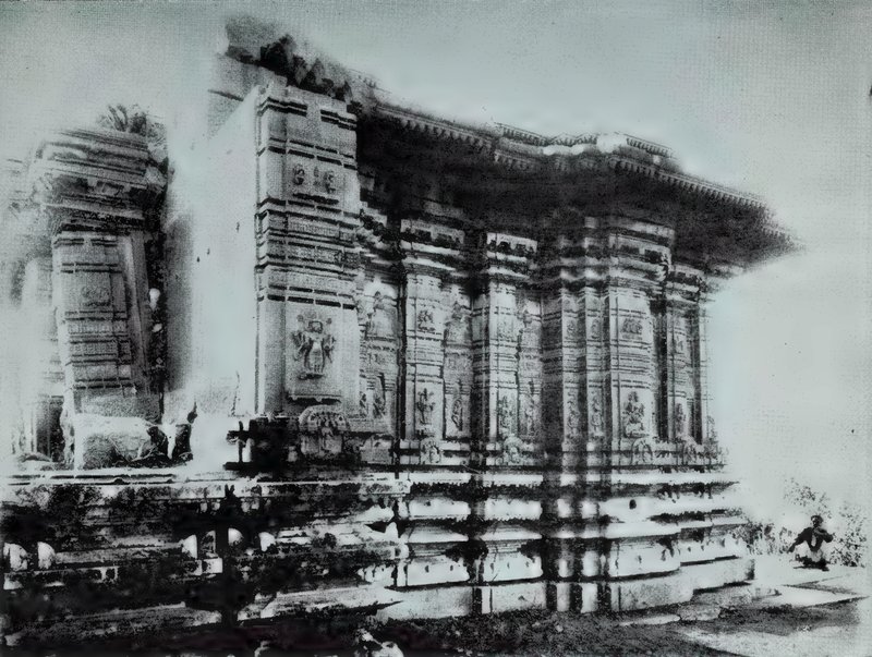 A temple seen from one corner, with outer walls covered with carved niches and pilasters, on a moulded base.