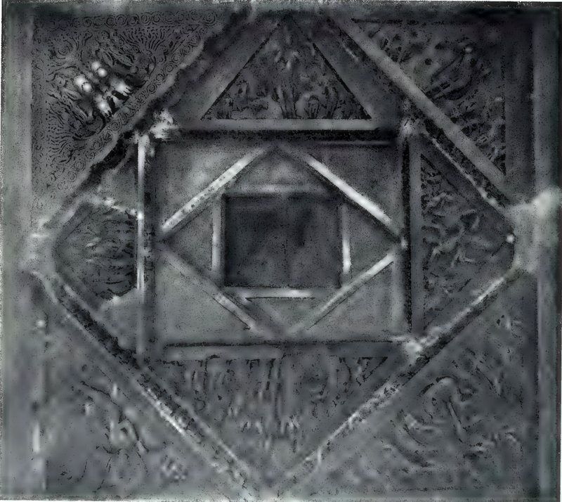 A square carved ceiling panel seen from below, with nested squares and diamonds framed by carved beams.