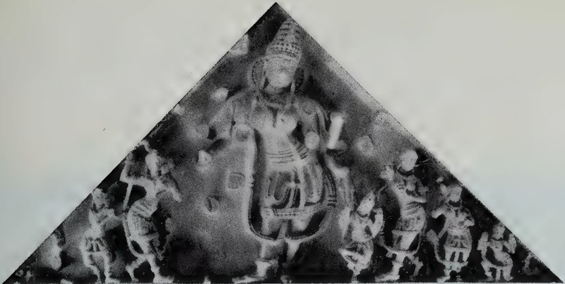 A triangular carved stone panel with a standing goddess at the centre and small statues along the base.