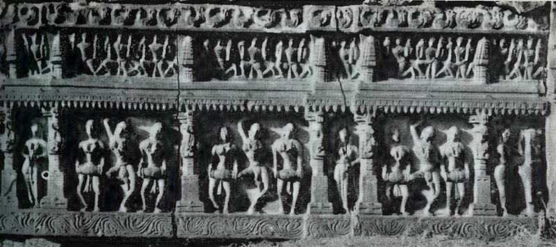 A carved frieze in two rows, with small statues above and dancers in pairs and threes between pillars below.