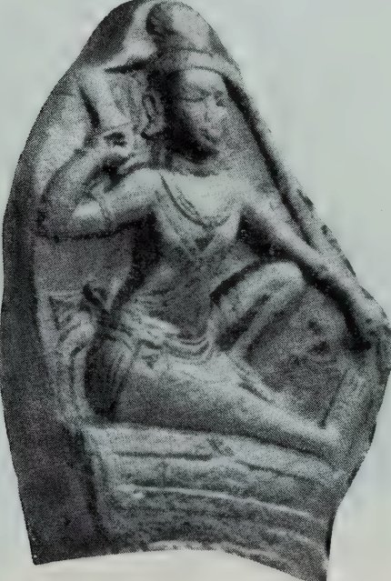A broken stone relief with an irregular outline, showing a seated man with one arm raised.
