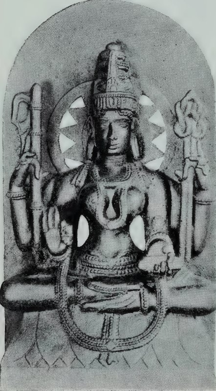 A seated four-armed goddess with crossed legs on a lotus base, with a halo behind her head, on a stele with a rounded top.