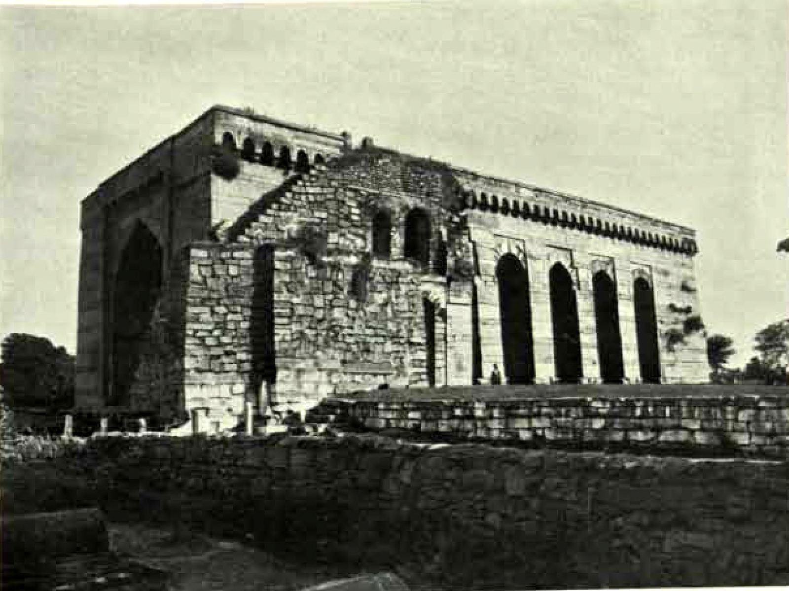 The long stone hall of the Khush Mahal seen from the north-west. Tall pointed arches line its side wall. A block of rough rubble masonry is built against one end.