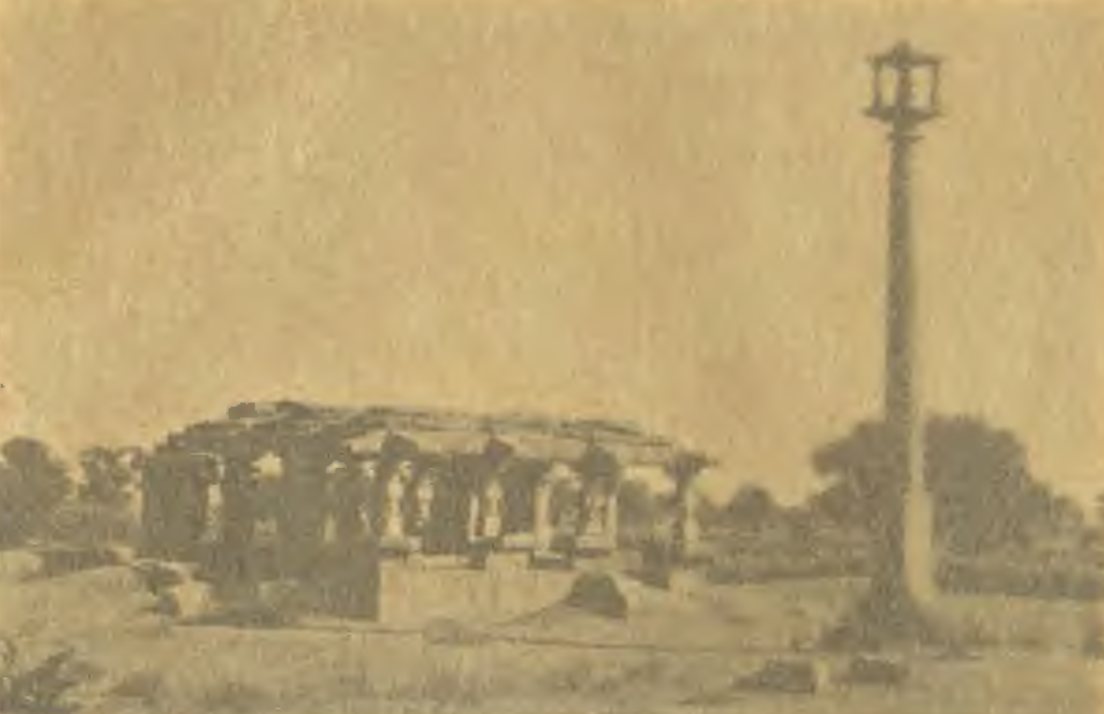 A tall slender stone pillar with a small pavilion at its top stands beside a low ruined hall of stone pillars.