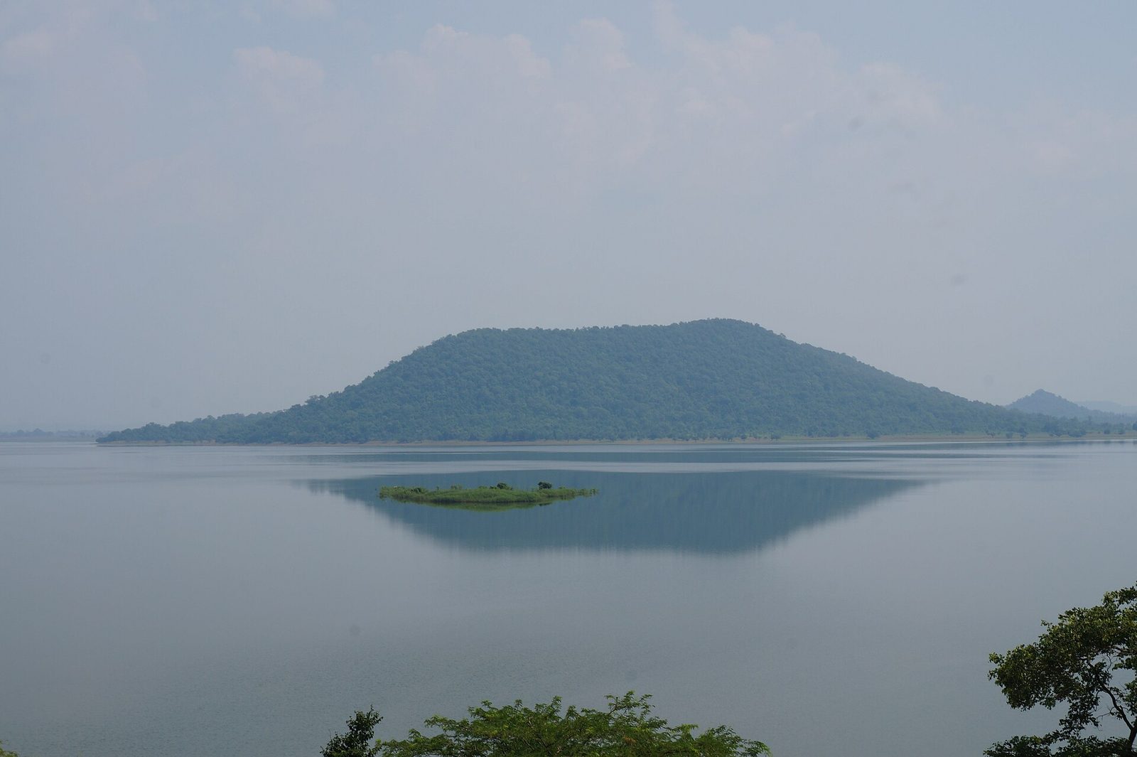Wide view across Pakhal Lake to a forested hill on the far shore, with a small island reflected in the still water