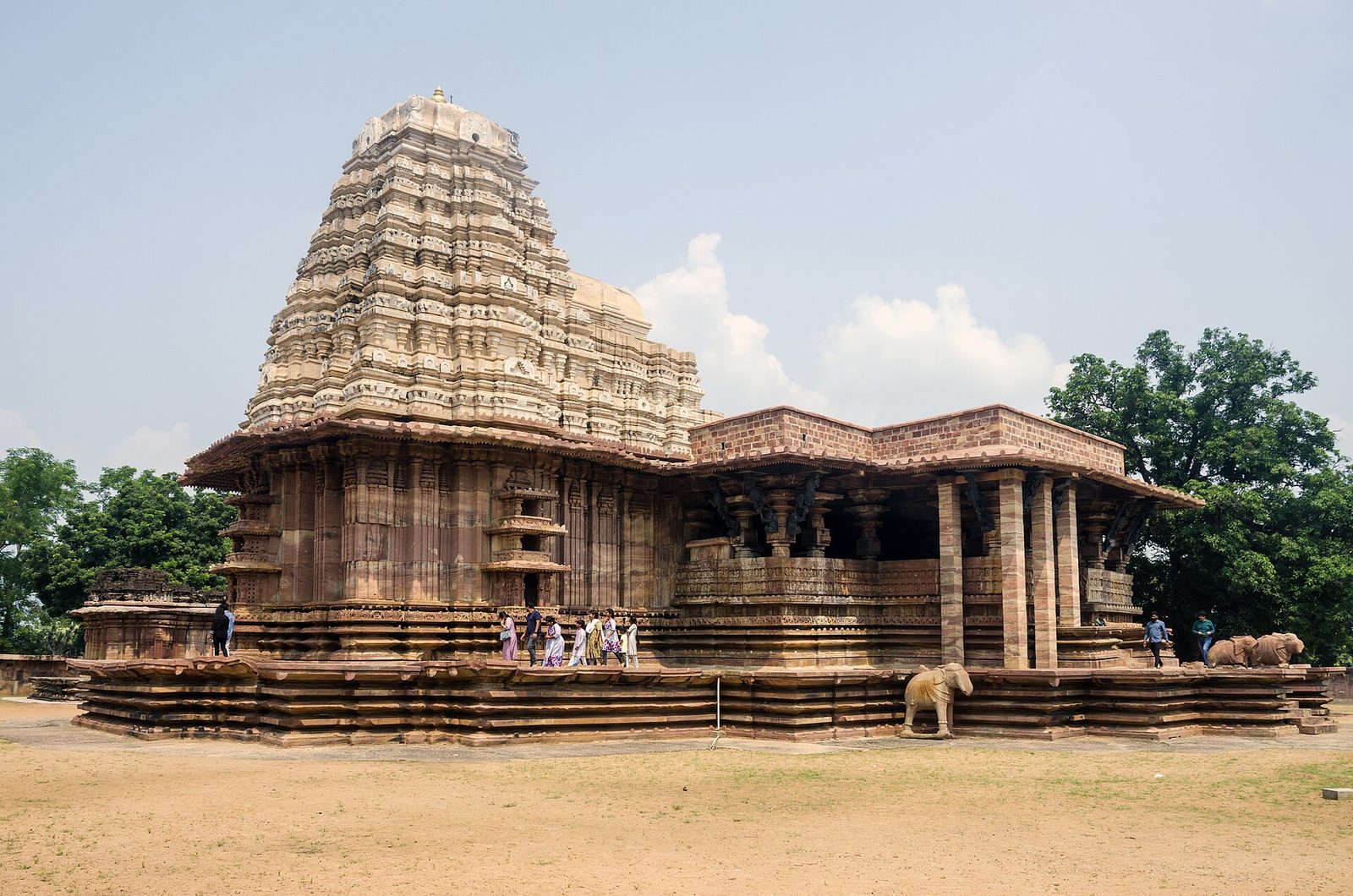 Ramappa Temple seen from the south-west. The pale, many-tiered vimana rises over the shrine, and the flat-roofed mandapa with projecting eaves extends to the right. Both stand on a broad moulded platform, and a stone elephant stands on its edge.